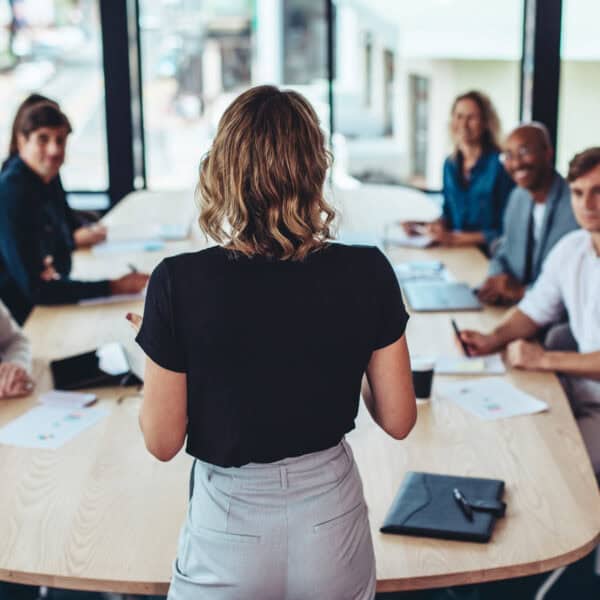 Rear view of a businesswoman addressing a meeting in office. Female manager having a meeting with her team in office boardroom.