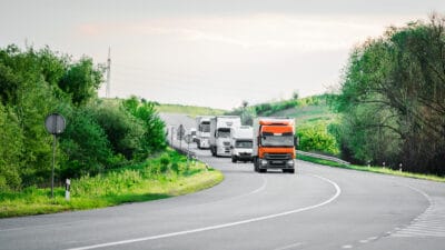 Arriving white truck on the road in a rural landscape at sunset